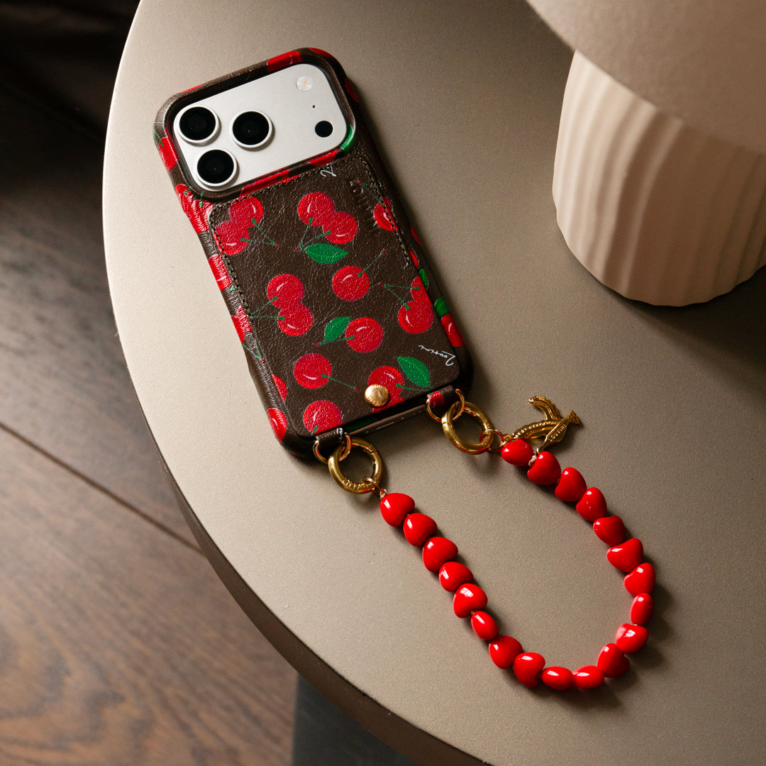 coque iphone en cuir imprimé cerises et bracelet de téléphone petites perles coeurs rouge