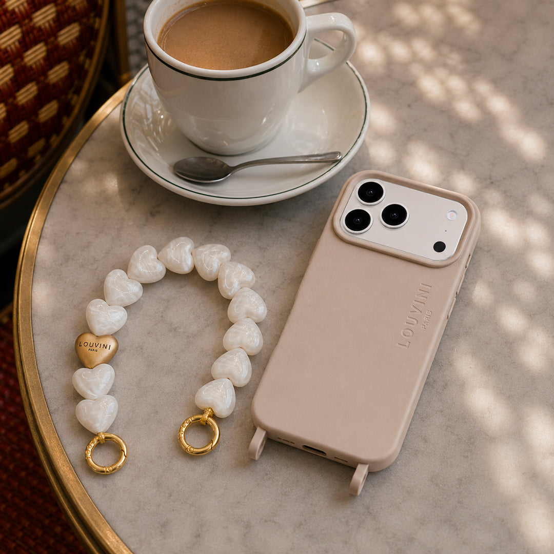 coque iphone beige taupe avec magsafe et anneaux et bracelet de telephone avec gros coeurs en résine perles blanches et anneaux dorés