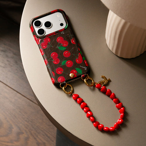 coque iphone en cuir imprimé cerises et bracelet de téléphone petites perles coeurs rouge