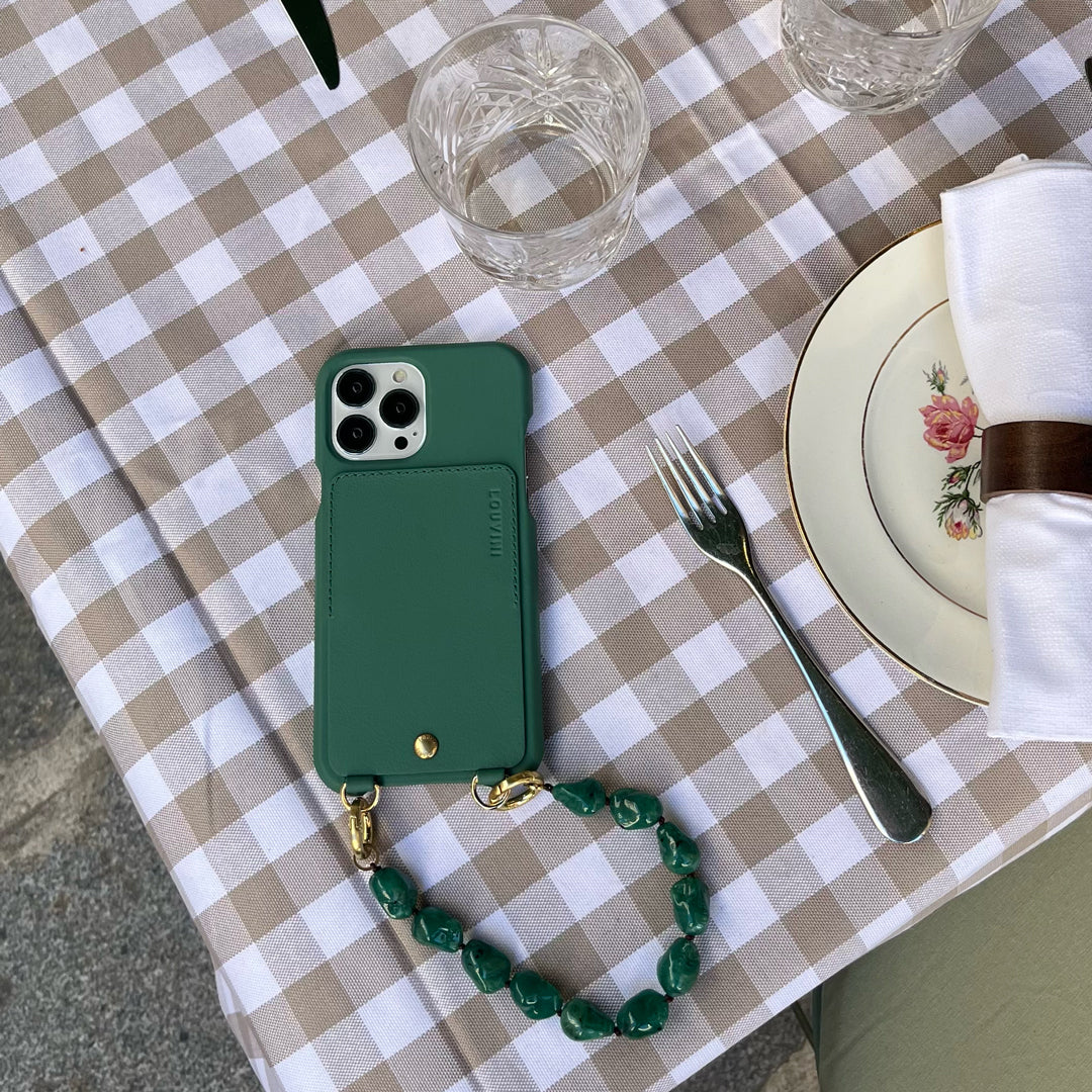 coque iphone en cuir vert emeraude avec porte cartes et anneaux et bracelet de téléphone vert à perles